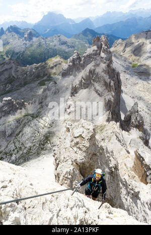 Jungen gutaussehenden männlichen Bergsteiger auf einem steilen und exponierten Fels klettert ein Klettersteig in Alta Badia in Südtirol Stockfoto