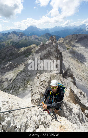 Jungen gutaussehenden männlichen Bergsteiger auf einem steilen und exponierten Fels klettert ein Klettersteig in Alta Badia in Südtirol Stockfoto