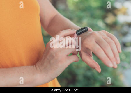 Frau Wanderer mit smart Armband während Trekking in der Natur. In der Nähe der weiblichen Händen mit Fitness, selektiven Fokus. Stockfoto