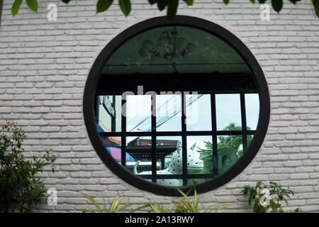 Runde Fenster, Ansicht von hinter einem Baum mit Reben und Blätter. Künstlerisch schöne abstrakte Fotografie Stockfoto