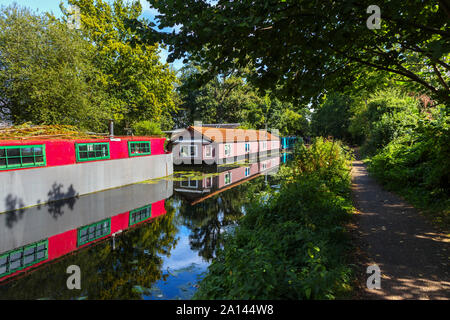 Red Hausboot fest vertäut am Ufer der Basingstoke Canal im Woodham Bereich der Woking, Surrey, Südosten, England, Grossbritannien Stockfoto