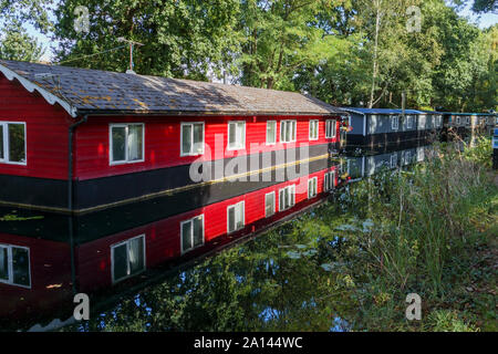 Red Hausboot fest vertäut am Ufer der Basingstoke Canal im Woodham Bereich der Woking, Surrey, Südosten, England, Grossbritannien Stockfoto