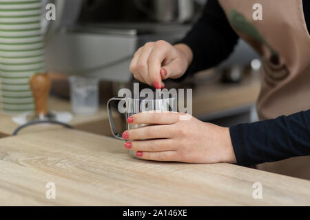 Eine Schürze barista gießt in eine Tasse heißen Kakao. Barista arbeiten in einem Coffee Shop. Stockfoto
