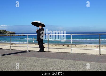 Mann mit Schirm für ein Foto posiert am Strand Stockfoto