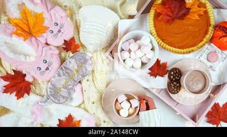 Gemütliche Herbst Thanksgiving im Bett flatlay Overhead mit gemütlichen Pullover, Hausschuhe, Socken und Fach mit Pumpkin Pie und heiße Schokolade mit Marshmallows. Stockfoto