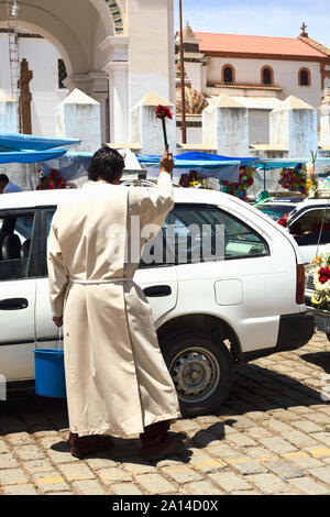 COPACABANA, BOLIVIEN - Oktober 20, 2014: Unbekannter Priester besprengen Weihwasser auf ein Auto an den Segen der Automobile in Copacabana, Bolivien Stockfoto