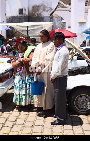 COPACABANA, BOLIVIEN - Oktober 20, 2014: Unbekannter Priester mit Besitzer eines Autos posieren für ein Foto auf die Segnung der Fahrzeuge in Copacabana Stockfoto