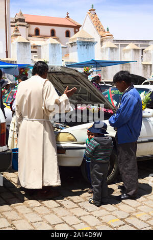 COPACABANA, BOLIVIEN - Oktober 20, 2014: Priester und sprach ein Gebet vor dem Öffnen der Motorhaube eines Autos bei der Segnung der Fahrzeuge in Copacabana, Bolivien Stockfoto