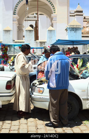 COPACABANA, BOLIVIEN - Oktober 20, 2014: Priester und sprach ein Gebet vor dem Öffnen der Motorhaube eines Autos bei der Segnung der Fahrzeuge in Copacabana, Bolivien Stockfoto