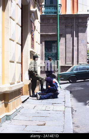 LA PAZ, BOLIVIEN - Oktober 11, 2014: Unbekannter shoeblack Reinigung die Stiefel von einem Mann in Uniform in La Paz, Bolivien Stockfoto