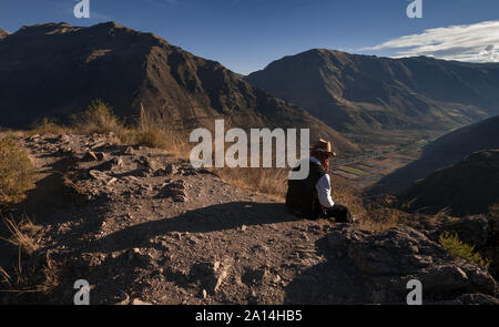 Pisac, Peru - 11. August 2011: ein Mann sitzt auf der Kante des Berges. Stockfoto