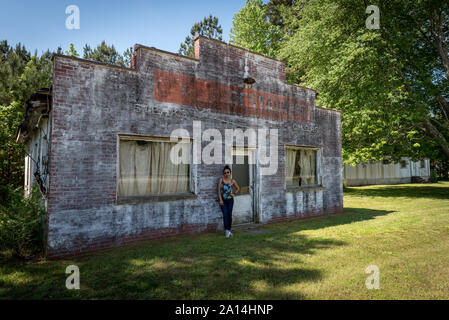 Asiatische Frau in Jeans und Turnschuhen vor verfallen und abondoned Restaurant in Virginia stehend Stockfoto