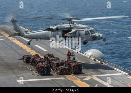 Ein MH-60S Seahawk Aufzüge Paletten von Munition aus dem Flight Deck der USS BONHOMME RICHARD. Stockfoto