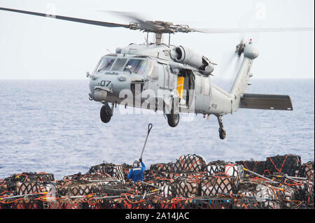 Ein MH-60S Seahawk Hubschrauber hebt Cargo aus dem Flight Deck der USNS Big Horn. Stockfoto