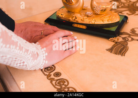 Die Hände des Brautpaares mit Hochzeit Ringe nach der Trauung auf einem luxuriösen Tabelle, close-up Stockfoto