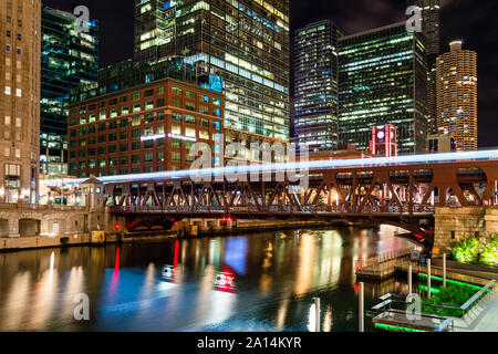 Ein Zug aus, die über den Chicago River durch die Innenstadt bei Nacht. Main Street in Chicago. Stockfoto