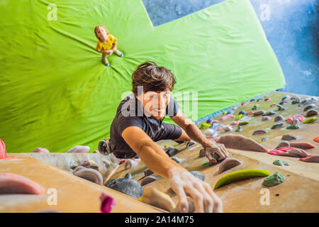 Muskulöse Mann üben Klettern auf einem Felsen an der Wand im Innenbereich Stockfoto