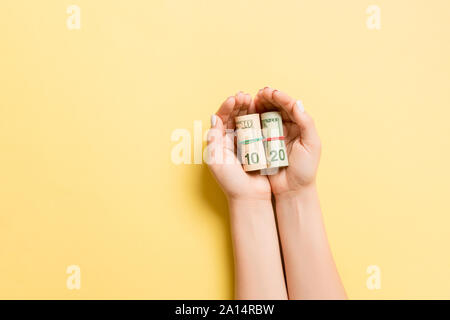 Bis Dollarscheine in weibliche Palmen auf bunten Hintergrund gerollt. Armut und schlechte Konzept. Stockfoto