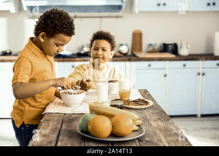 Cute afroamerikanischen Zwillinge Frühstücken vor der Schule. Stockfoto