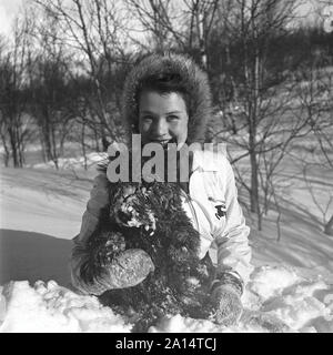 Winter in den 1940er Jahren. Eine junge Frau im Schnee mit ihrem Hund. Schweden 1943. Kristoffersson Ref D 71-2 Stockfoto