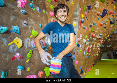 Muskulöse Mann üben Klettern auf einem Felsen an der Wand im Innenbereich Stockfoto