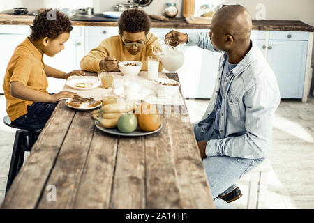 Familie von Papa und zwei Jungs beim Frühstück in der Küche. Stockfoto