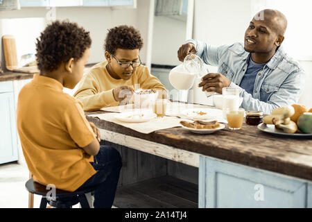Brüder am Tisch sitzen und zu warten, bis die Vati ihre Milch giessen. Stockfoto