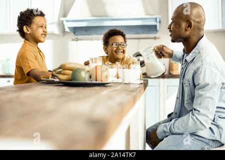 Drei - zwei Jungen und Mann - Sitzen am Tisch, Mittagessen und Lachen. Stockfoto