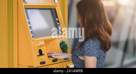 Seitenansicht des asiatischen Frauen ziehen das Geld von einer Bank mit Geldautomat in der Mall Stockfoto