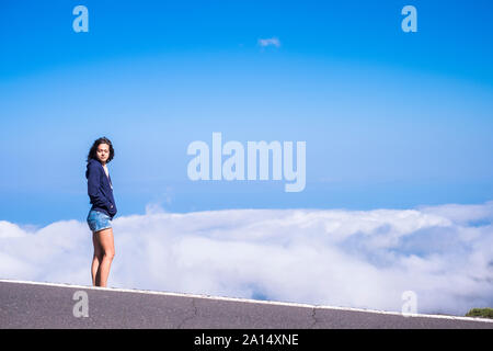 Träumen und Freiheit Konzept mit schönen hohen, stehenden jungen Frau mit geschlossenen Augen und Wolken und blauer Himmel im Hintergrund Stockfoto