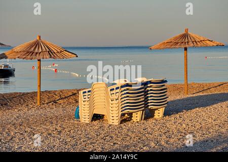 Liegen und Sonnenschirme am Strand bei Sonnenaufgang Stockfoto