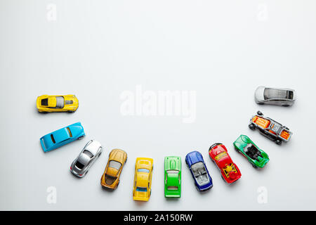 Viele farbige kleine Spielzeugautos auf grauem Hintergrund Stockfoto