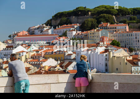 Zwei Touristen am Arco da Rua Augusta (Rua Augusta Arch) Aussichtsplattform mit Sao Jorge und Blick auf die Stadt hinter in Lissabon, Portugal. Stockfoto