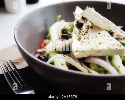 Closeup leckeren griechischen Salat mit frischem Gemüse und Schafskäse mit Gewürzen und in Ton Schüssel serviert. Stockfoto