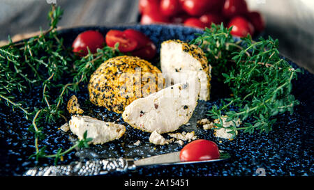 Käse belper Knolle, die in den Gewürzen roten und schwarzen Pfeffer und Kräutern der Provence. Kleine hausgemachte Kugeln von Käse Belper. Delikatesse runde kleine Käse mit Schwarz Stockfoto