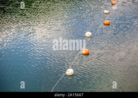 Seil mit weißen und gelben Einschränkung Markierungen auf dem Wasser Oberfläche für ein Verbot von Schwimmen im See oder Meer. Stockfoto