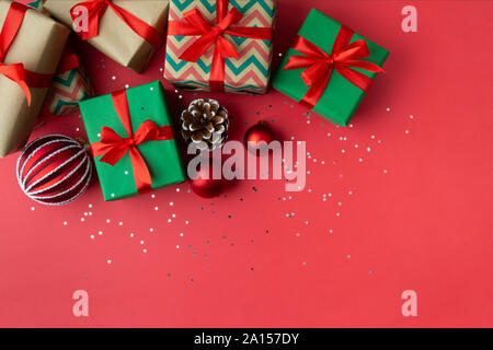 Weihnachten Geschenk Boxen mit Pine Cone, Ornamente und sternförmigen Glitzer auf einem roten Hintergrund. Flach Stockfoto