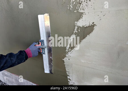 Arbeitnehmer, die isolierte Wand mit Lösung von Klebstoff überputzbar Polystyroldämmung. Stockfoto