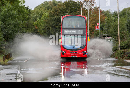 Eine London Bus gehen durch einen teilweise überschwemmte Straße in der Nähe von Colnbrook, West London. Das Met Office hat eine gelbe Wetter Warnung für viel von England und Wales heute herausgegeben, mit Überschwemmungen in einigen Bereichen zu rechnen. Stockfoto