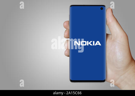 Ein Mann hält ein Smartphone mit dem Logo der Firma Nokia im OMX Stockholm aufgeführt. Grauen Farbverlauf im Hintergrund. Credit: PIXDUCE Stockfoto