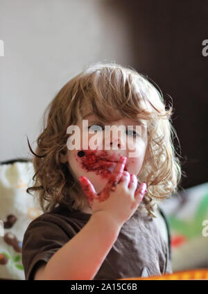 Ein Jahr alten Baby Mädchen essen leckere Heidelbeeren und schwarzen Johannisbeeren Kuchen mit ihrem Gesicht ganz schmutzig. Stockfoto