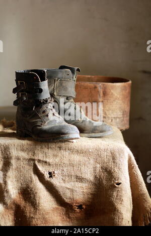 Alte verstaubte vintage Stiefel stehen auf Leinwand mit Bohrungen und Blutflecken Stockfoto