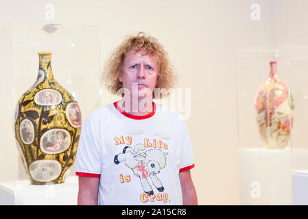 London, Großbritannien. 24. September 2019. Artist Grayson Perry stellt neben (L) 'Suchen nach Authentizität", 2018, einer von mehreren glasierte Keramik, an einen Fotoauftrag seine erste Einzelausstellung zu starten, 'Super reichen Innenausstattung', am Victoria Miro Mayfair Galerie. Neue Arbeit einschließlich der Töpfe, Skulptur, große Fotoprints eine Tapisserie und einen Teppich sind auf dem Display 25. September bis 20. Dezember 2019. Credit: Stephen Chung/Alamy leben Nachrichten Stockfoto