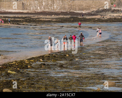 Menschen zu Fuß auf eine teilweise eingetaucht Causeway in Marazion, Cornwall Stockfoto