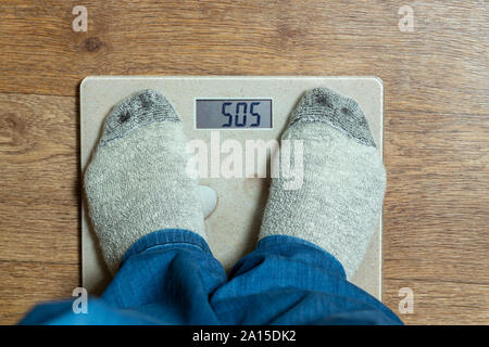 Ein Mann ist auf der Waage gewogen, Ansicht von oben. COC Inschrift Stockfoto