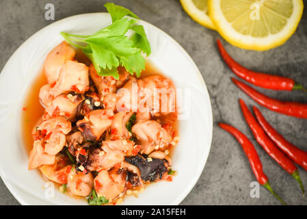 Oktopus Salat mit Zitrone, Chili auf weiße Platte/squid gegrillt Vorspeise essen heiß und würzig Chili Sauce Meeresfrüchte zubereitet auf dunklem Hintergrund diente, zu Stockfoto