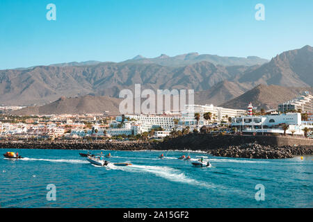 Teneriffa, Spanien - August 2019: Motorboote am Ozean Küste mit Hotels in Hintergrund in Playa de Las Americas / Costa Adeje, Teneriffa Stockfoto