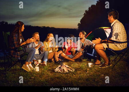 Eine Gruppe von Menschen durch die Lagerfeuer sitzen neben dem Zelt in der Nacht im Sommer in den Herbst. Stockfoto