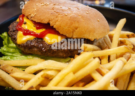Burger, Hamburger mit Rindfleisch, Pommes Frites, Ketchup, Käse und Salat, ungesunde Nahrung Stockfoto