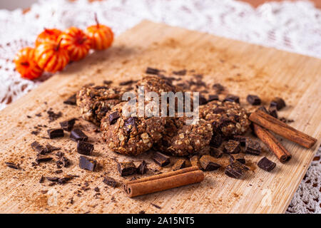 Schokolade Cookies auf Holztisch mit Zimtstangen. Herbst essen Foto mit Kürbis. Stockfoto